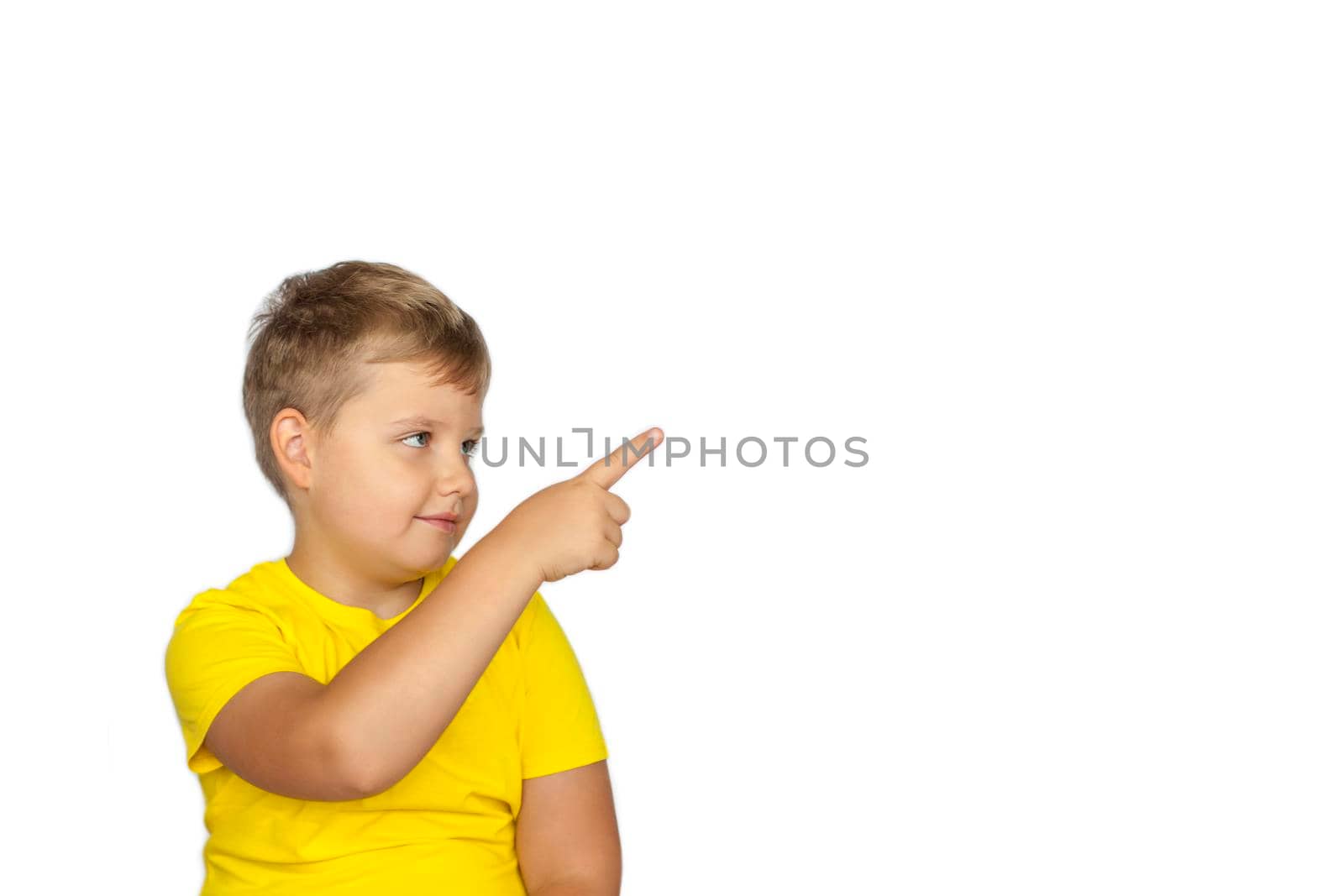 A boy in a yellow T-shirt on a white background points his fingers at something. The concept of a banner with information. Space for the text. Concepts