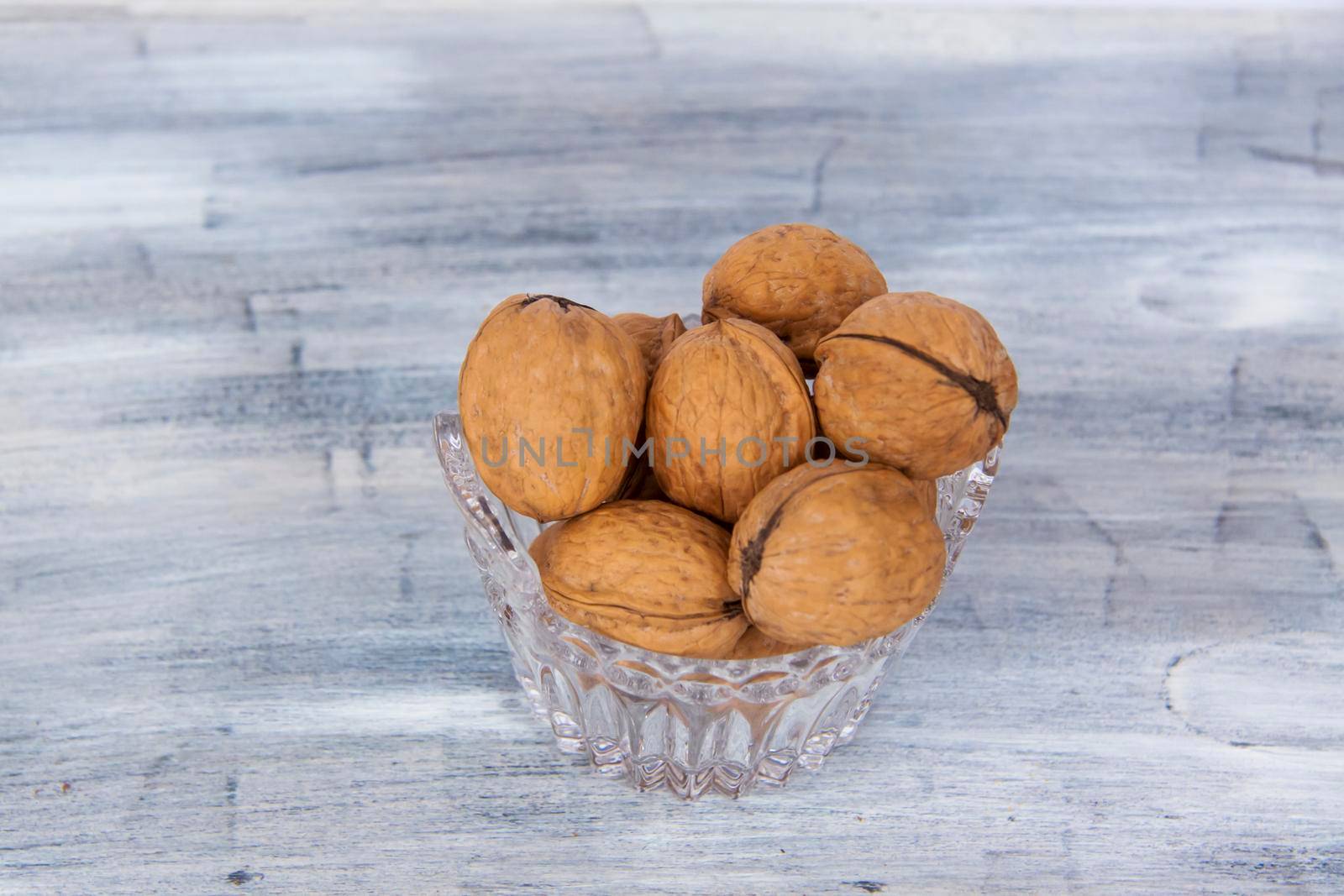 Walnuts in a shell on a painted background in a crystal vase. Healthy nuts. Walnuts. 