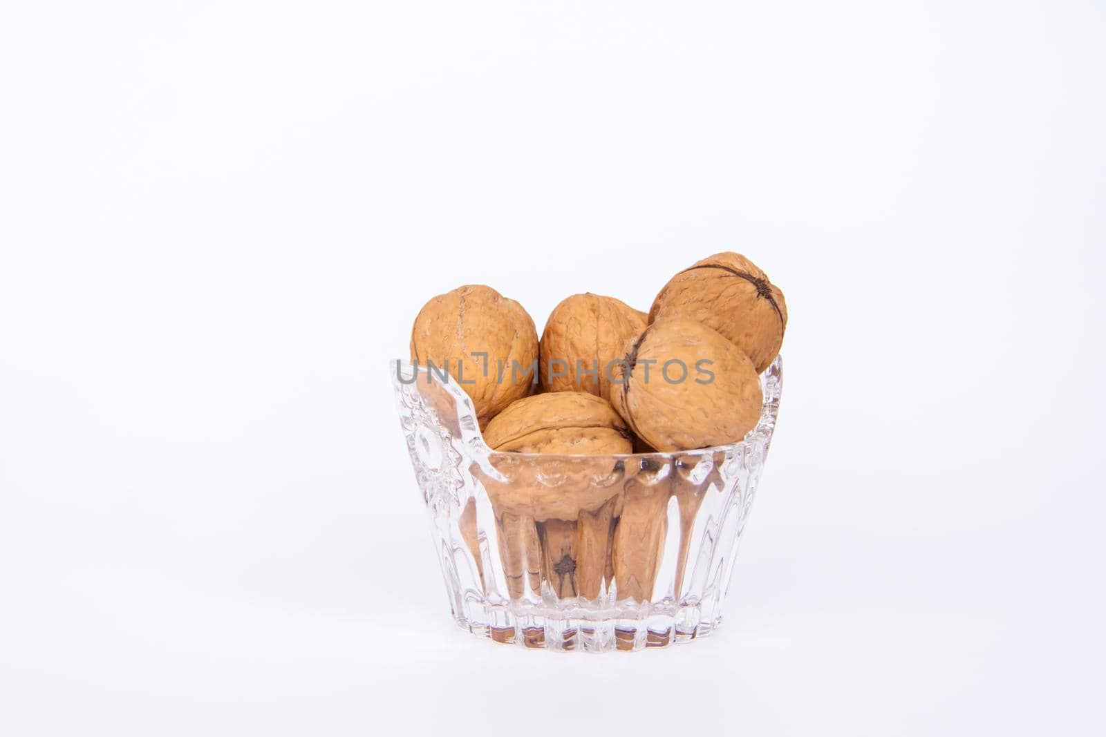 Walnuts in a shell on a white background in a crystal vase. Healthy nuts. Walnuts.