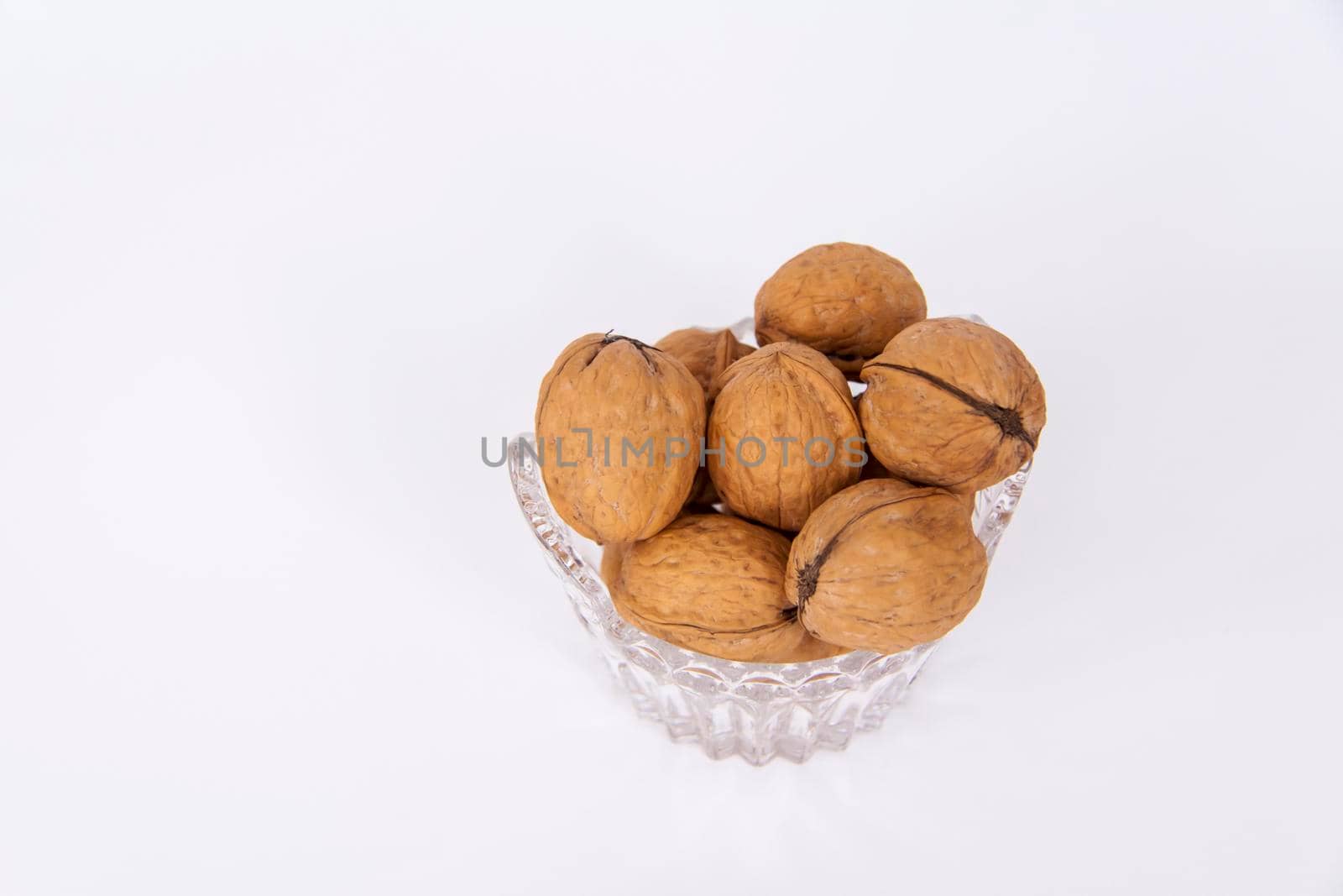Walnuts in a shell on a white background in a crystal vase. Healthy nuts. Walnuts.