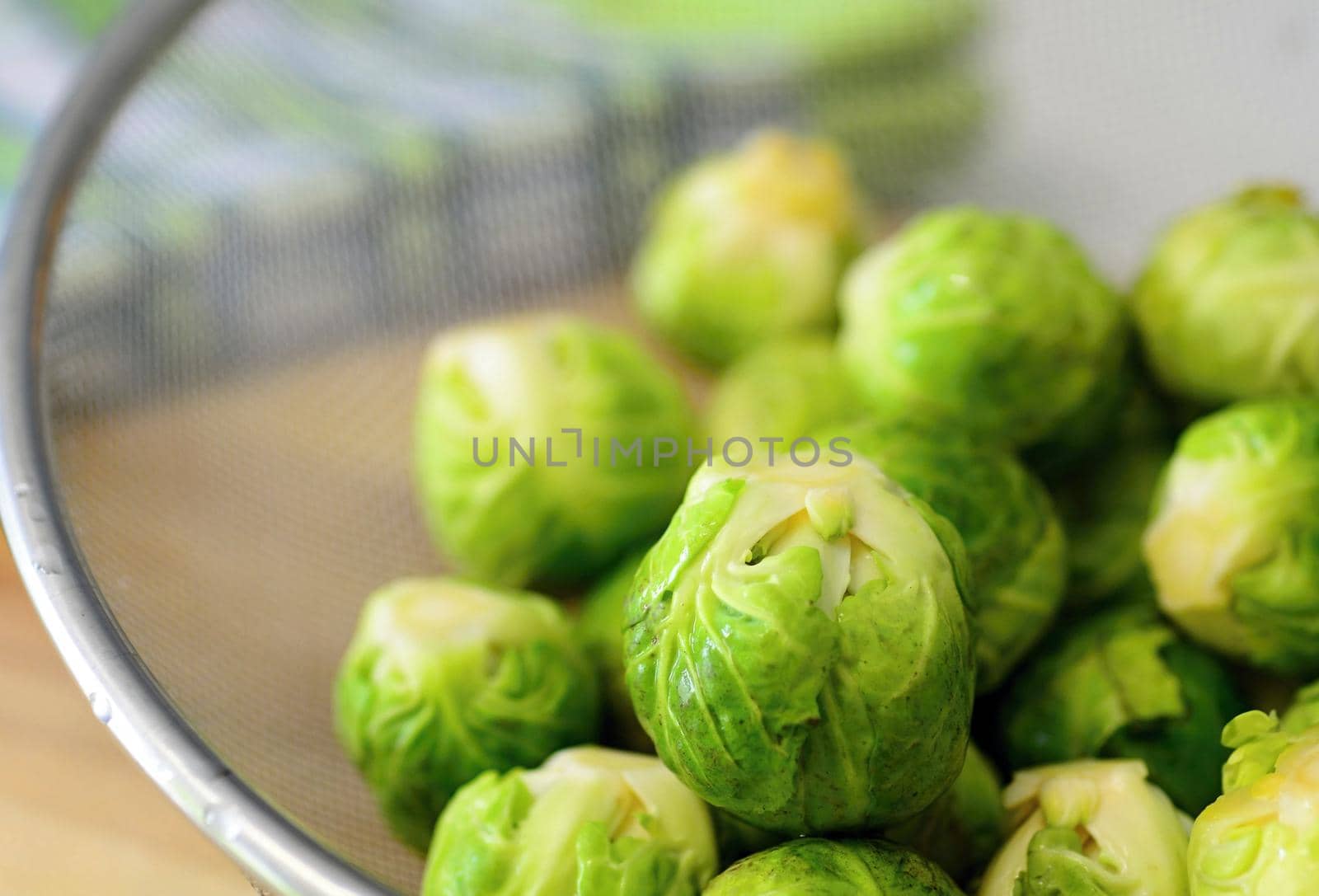 Heap of fresh green brussels sprouts in colander.