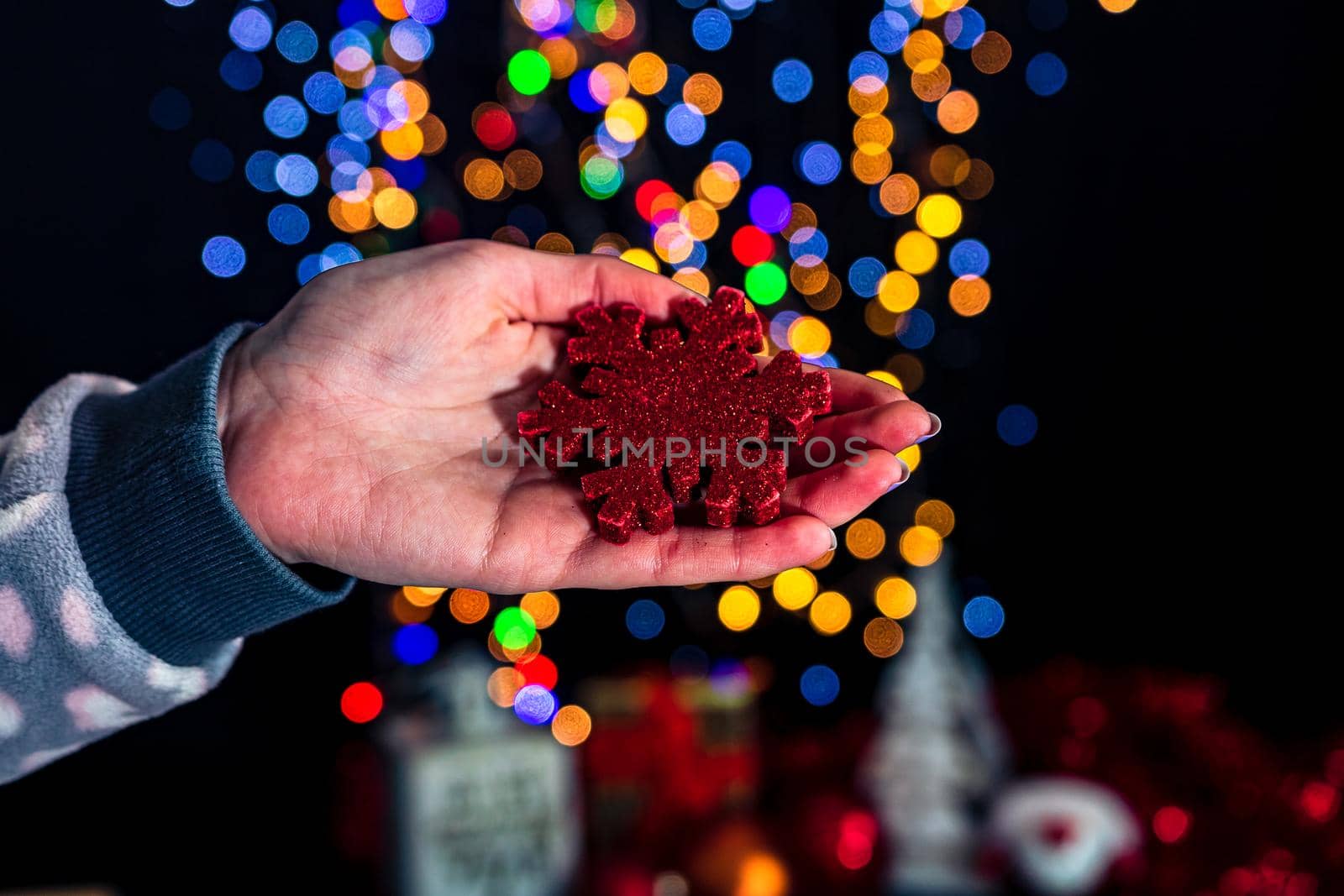 Holding Christmas snowflake decoration isolated on background with blurred lights. December season, Christmas composition.