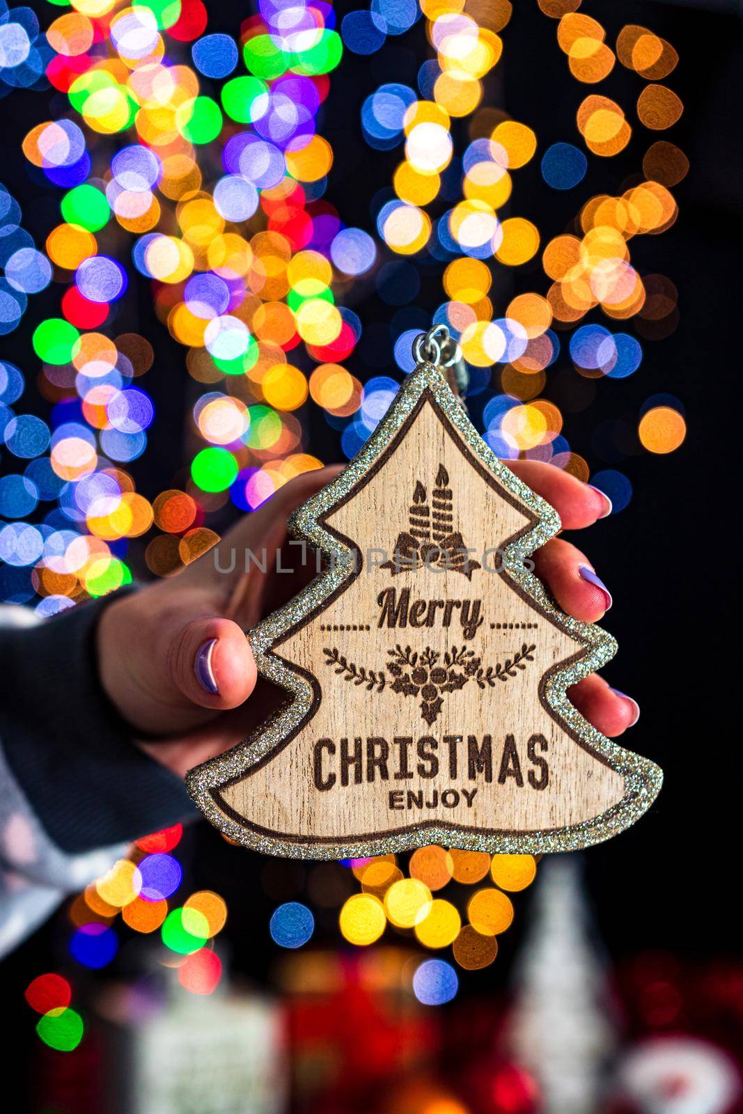 Holding Christmas decoration isolated on background with blurred lights. December season, Christmas composition.