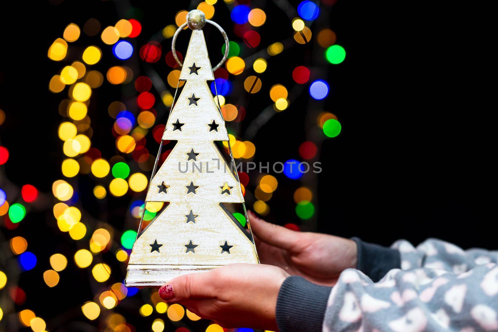 Woman's hands hold christmas decoration. Christmas and New Year holidays background, winter season with Christmas ornaments and blurred lights