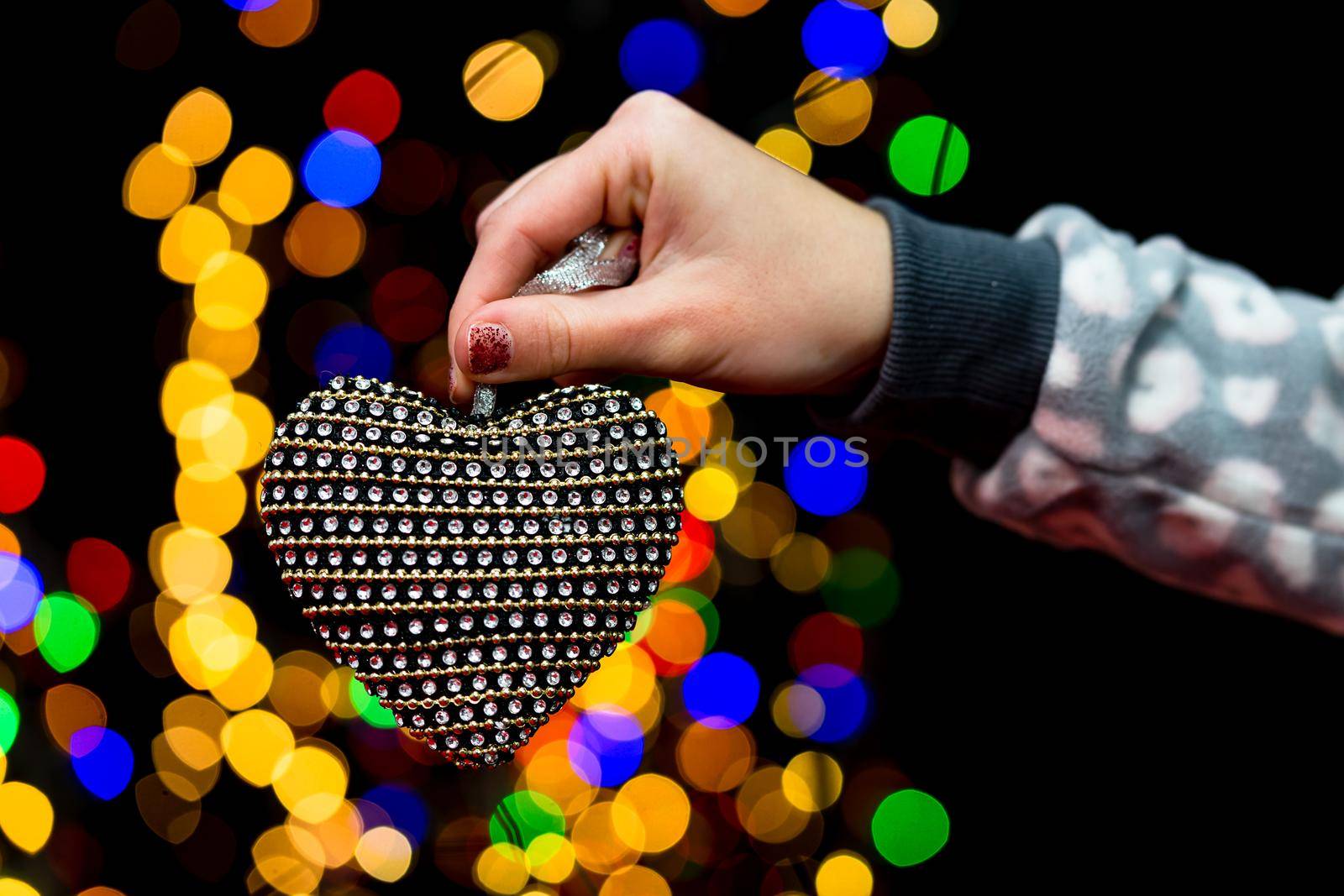 Woman's hands hold christmas decoration. Christmas and New Year holidays background, winter season with Christmas ornaments and blurred lights