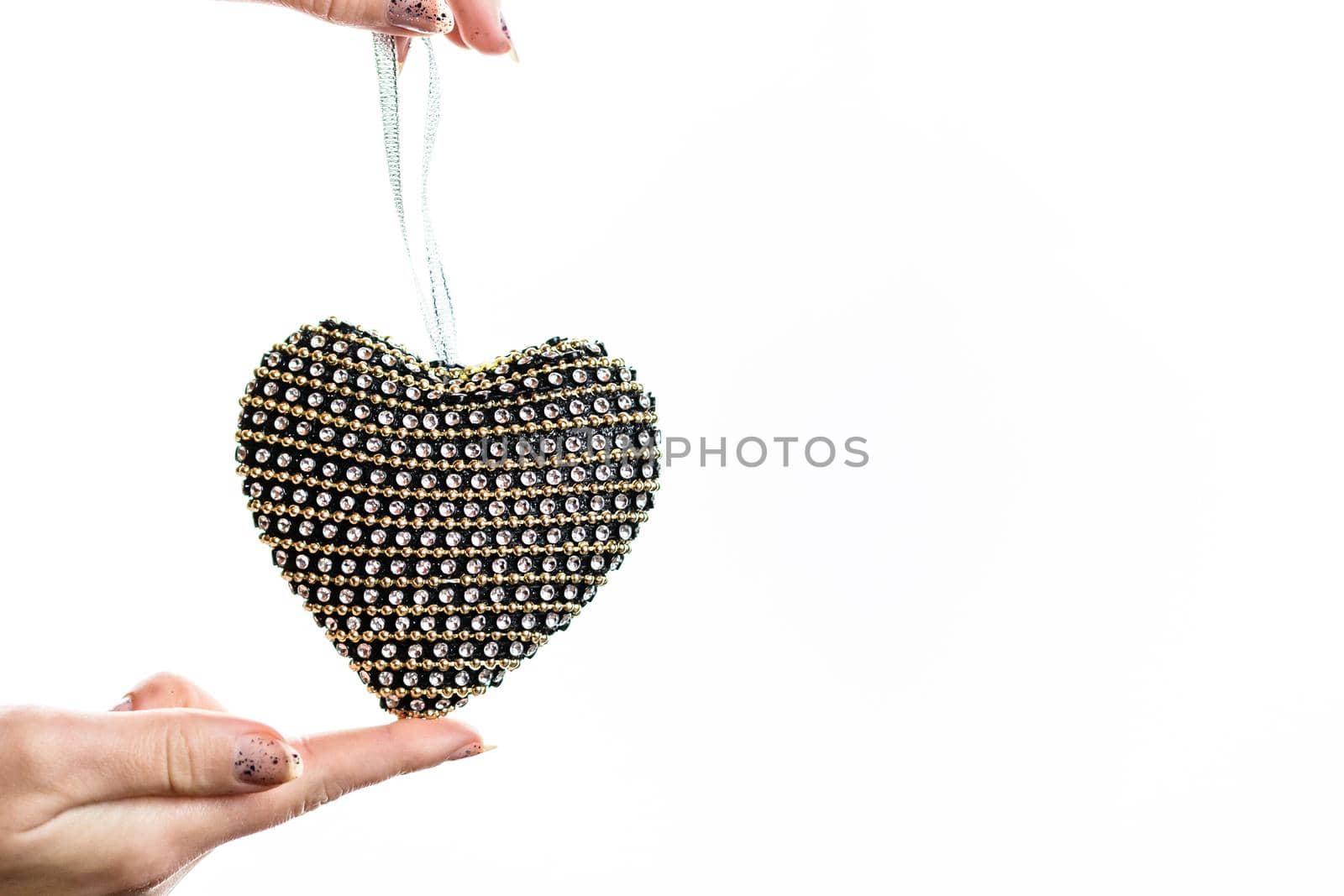 Hand holding heart shaped decoration isolated on white. by vladispas