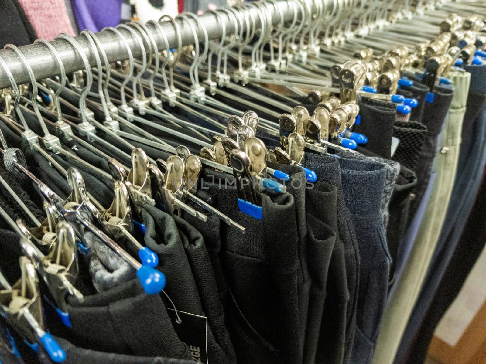 A row of hangers with cheap pants in the store in a market. Close-upw with selective focus and background blur.