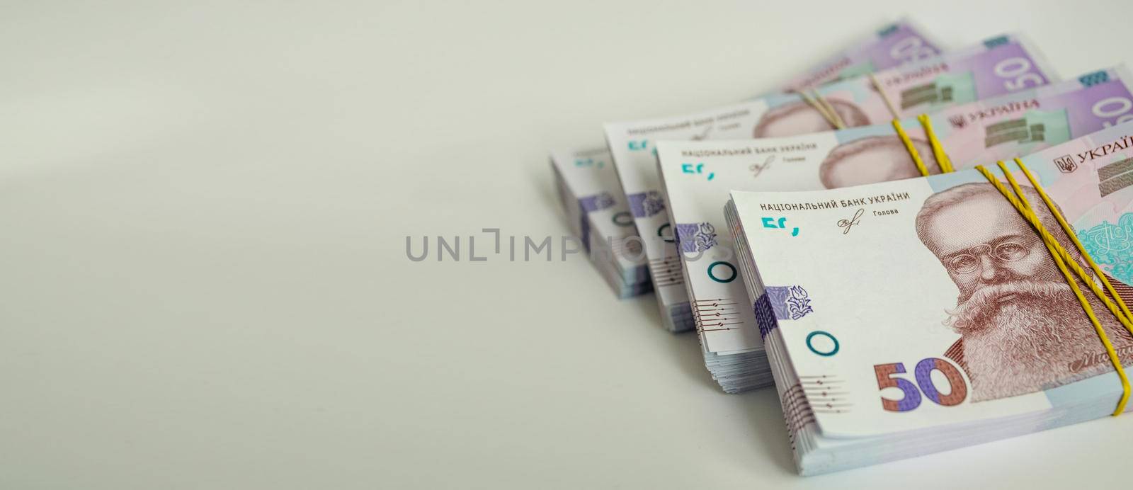 Bundles of 50 hryvnia banknotes are stacked on a light gray background. Financial concept.