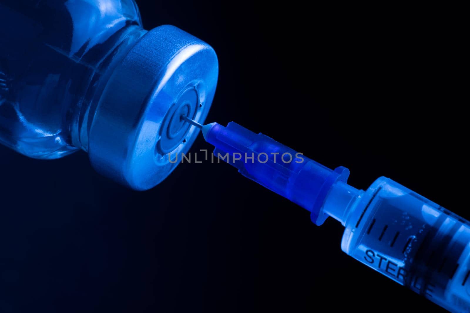 The drug is drawn into a syringe. Vaccine bottle. Medical chemical preparation and syringe under ultraviolet light. Narcotic drug.
