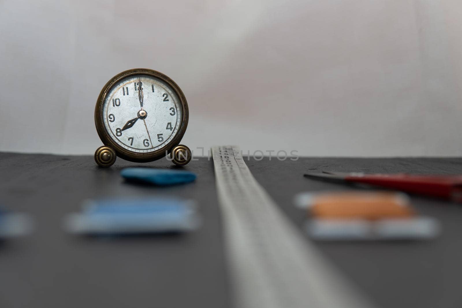 Clock surrounded by sewing utensils such as needle, thread and sewing tape measure. by xavier_photo