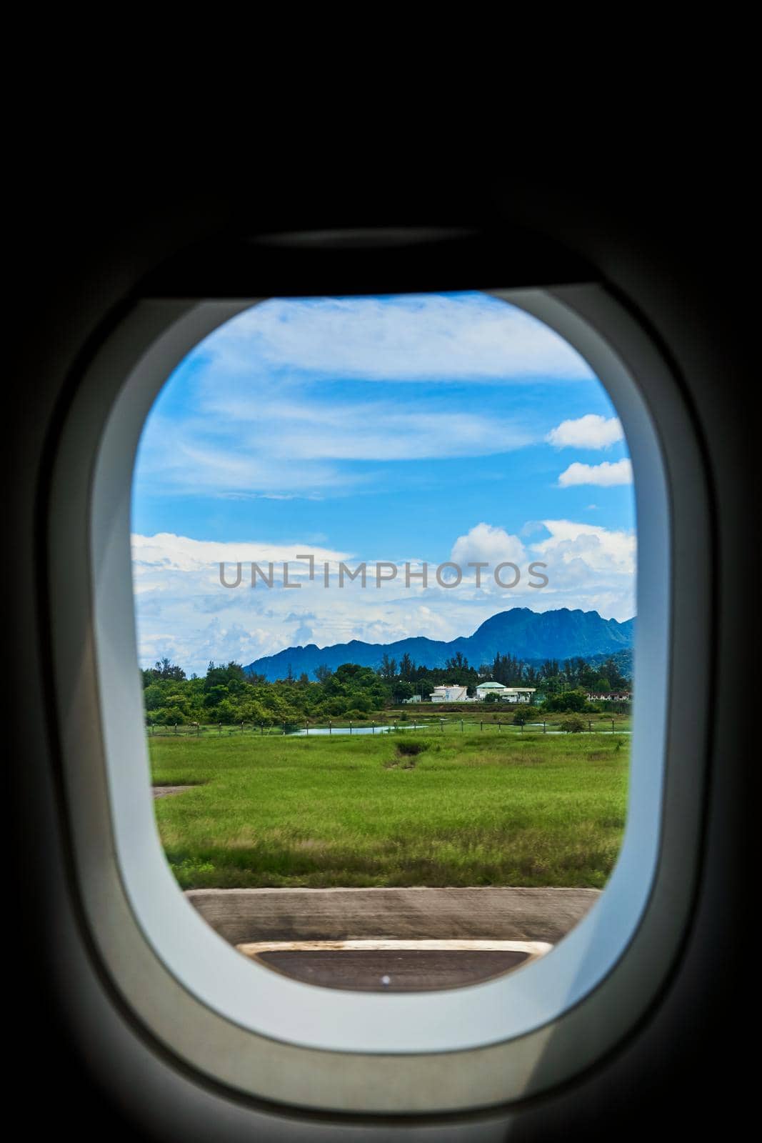 View from the window of an airplane on the runway of a tropical island.