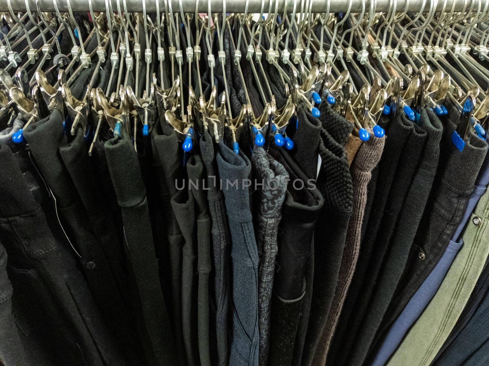 A row of hangers with cheap pants in the store in a market. Close-upw with selective focus and background blur.