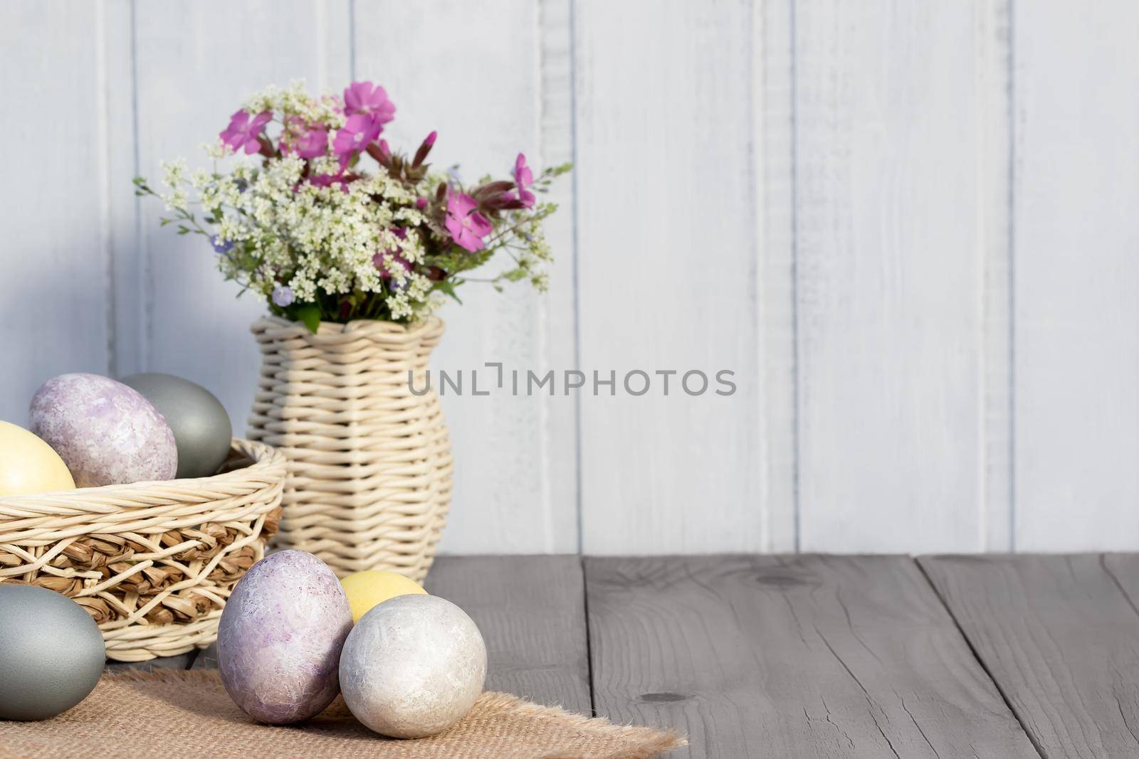 Easter composition - several eggs painted with natural dyes and wildflowers in a vase.