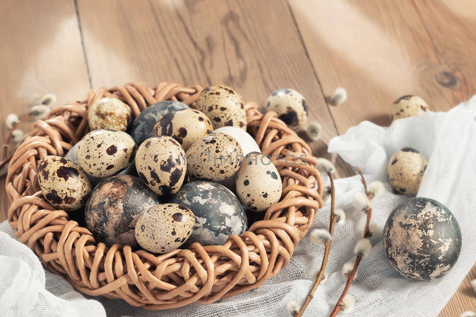 Easter composition - Easter eggs painted with natural dyes in a wicker nest on a wooden table, copyspace by galsand