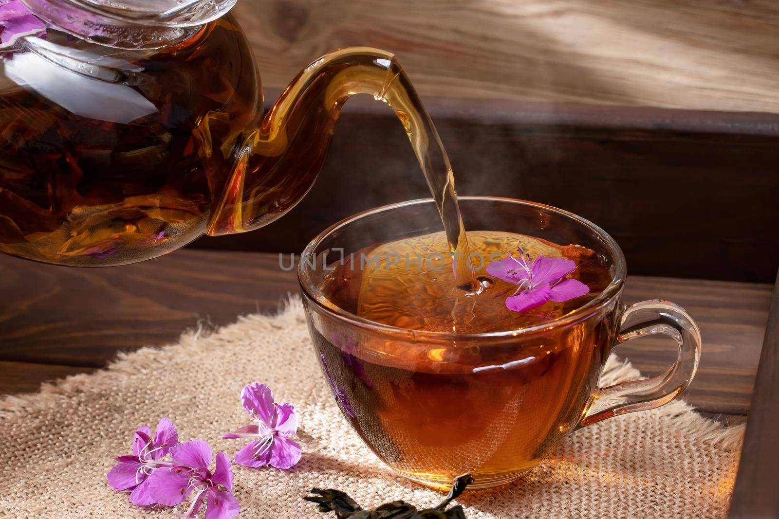 Pouring fireweed herbal tea into a transparent cup.