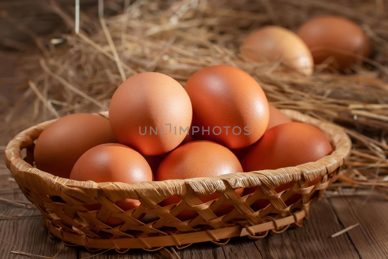 Fresh brown chicken eggs in a basket and in a nest from hay in a barn by galsand