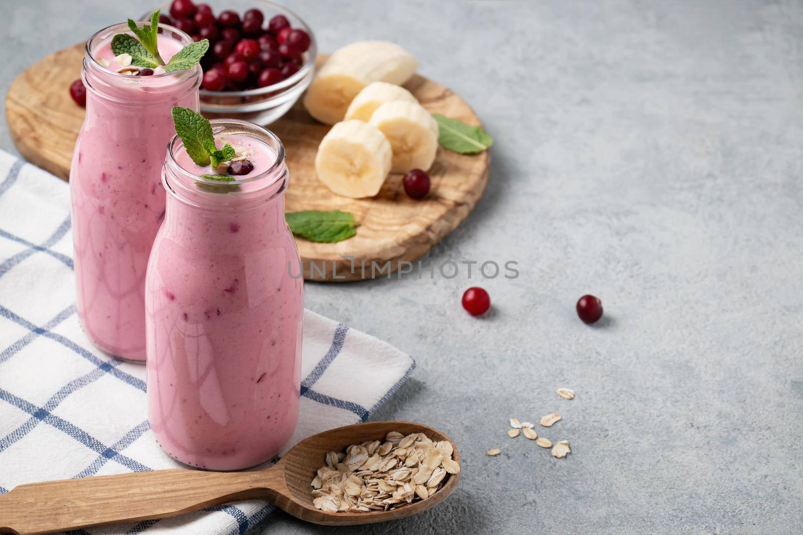 Homemade yogurt smoothie with banana, cranberry and oatmeal, copy space.