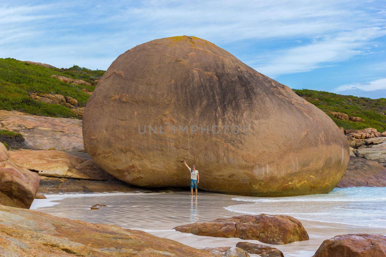 young caucasian man in front of a huge rock at Lucky Bay, Cape Le Grand National Park near Esperance, Australia by bettercallcurry