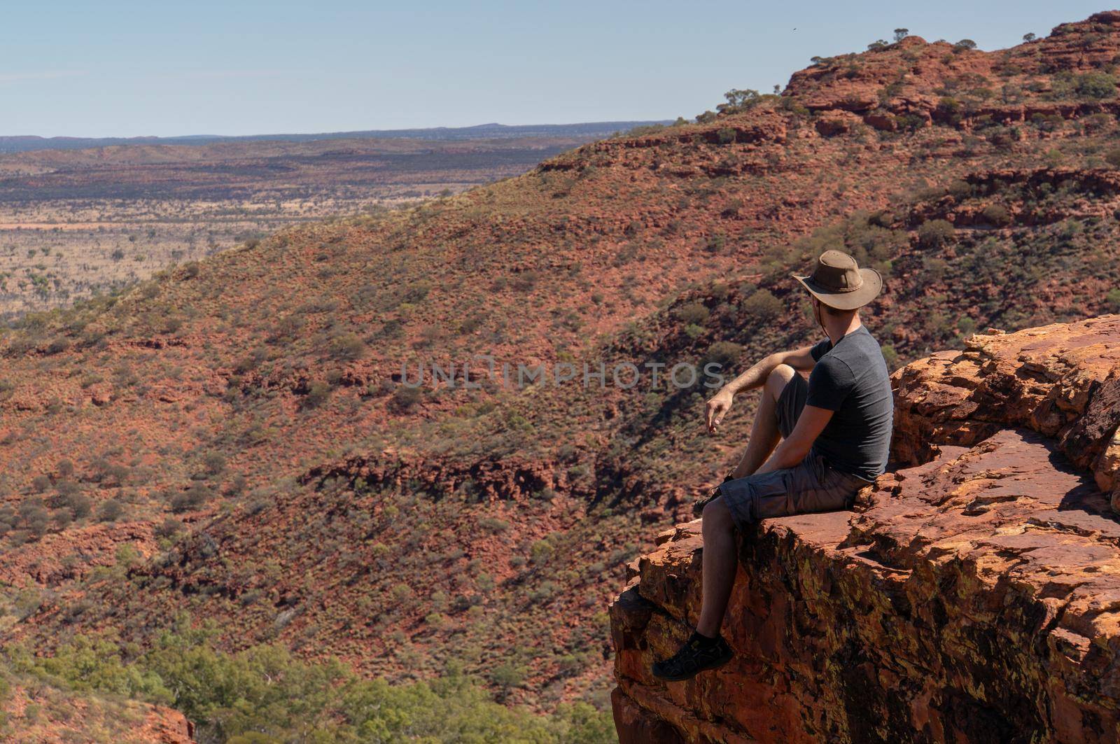 young man enyoing view of the a Canyon and standing on the edge of a cliff, Watarrka National Park, Northern Territory, Australia by bettercallcurry