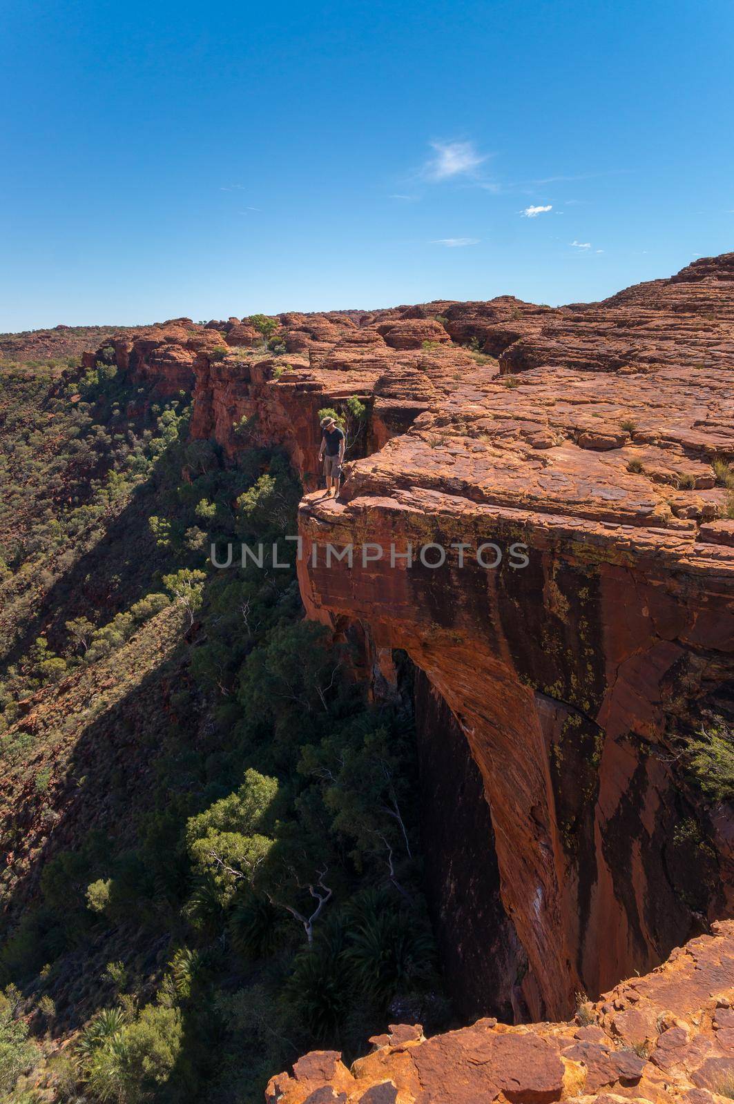 young man enyoing view of the a Canyon and standing on the edge of a cliff, Watarrka National Park, Northern Territory, Australia by bettercallcurry