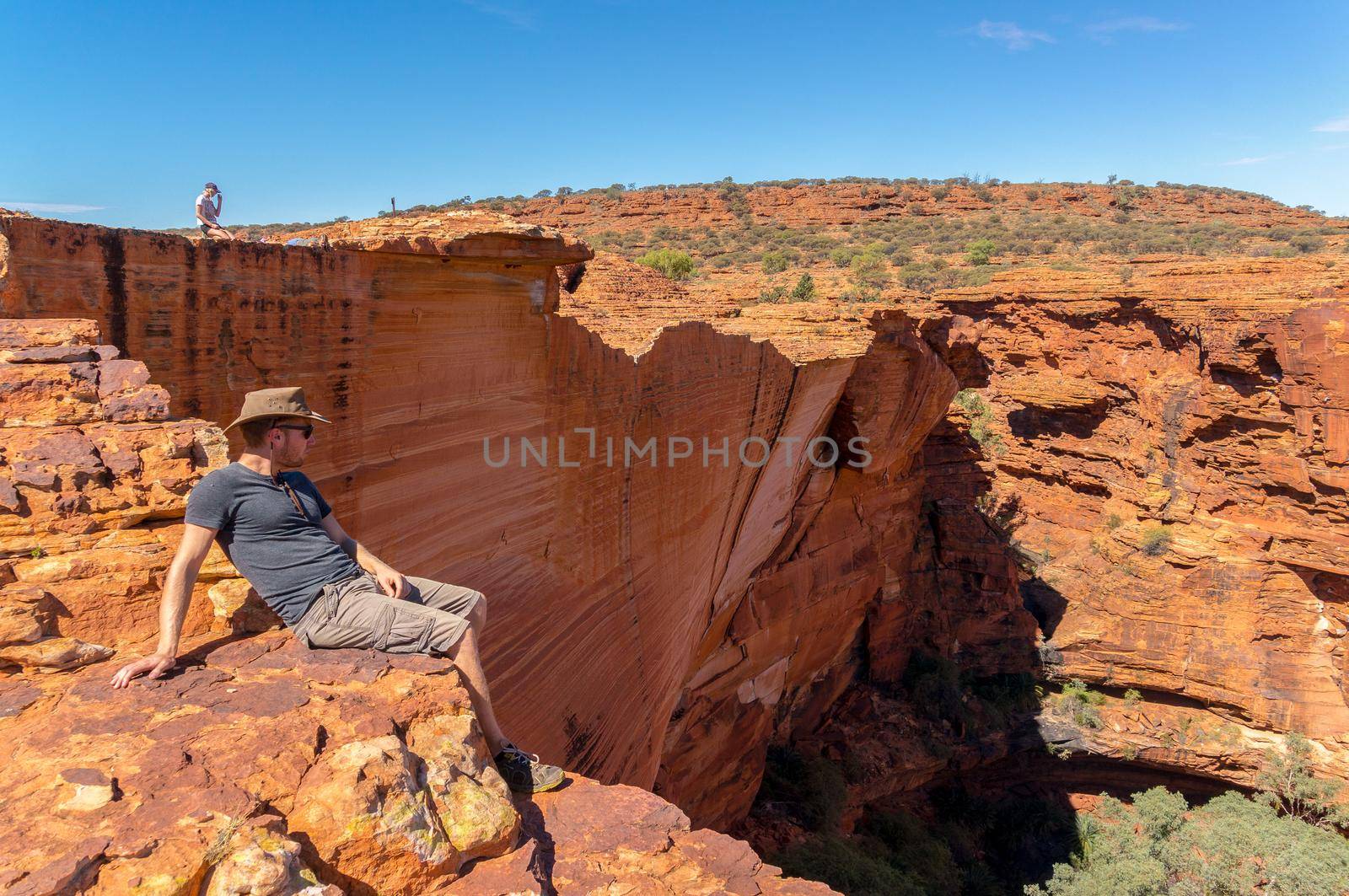 young man enyoing view of the a Canyon and standing on the edge of a cliff, Watarrka National Park, Northern Territory, Australia by bettercallcurry