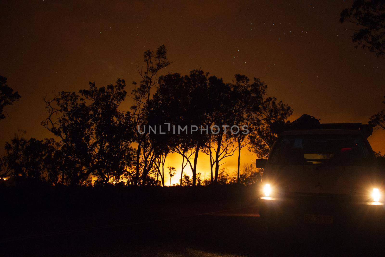 car driving away from a bushfire, forest are really bright because of the fire, litchfield national park, australia