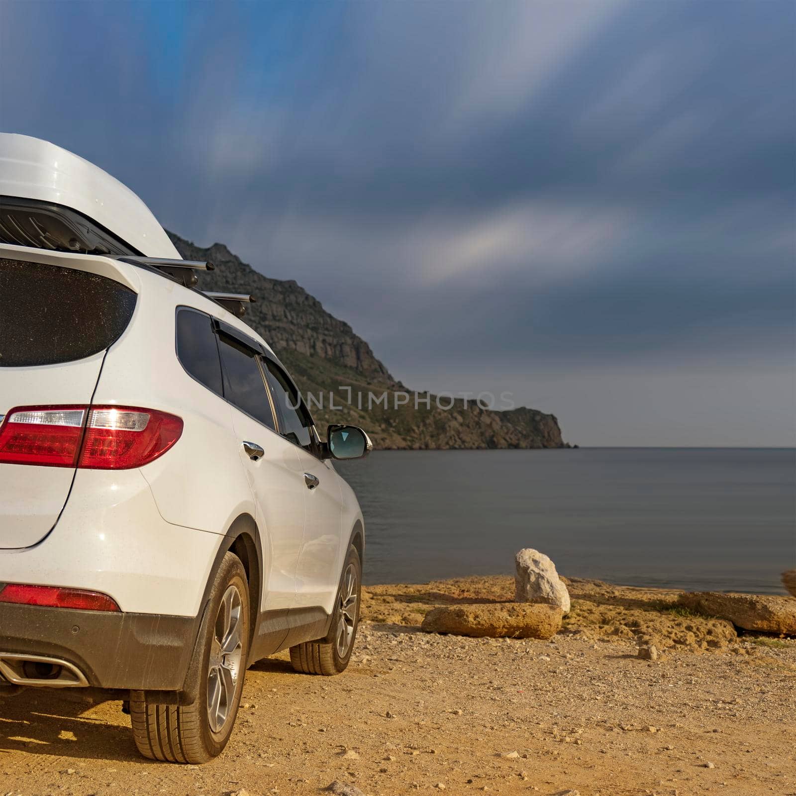 A large white car in front of the sea at the mountain Meganom in Crimea.