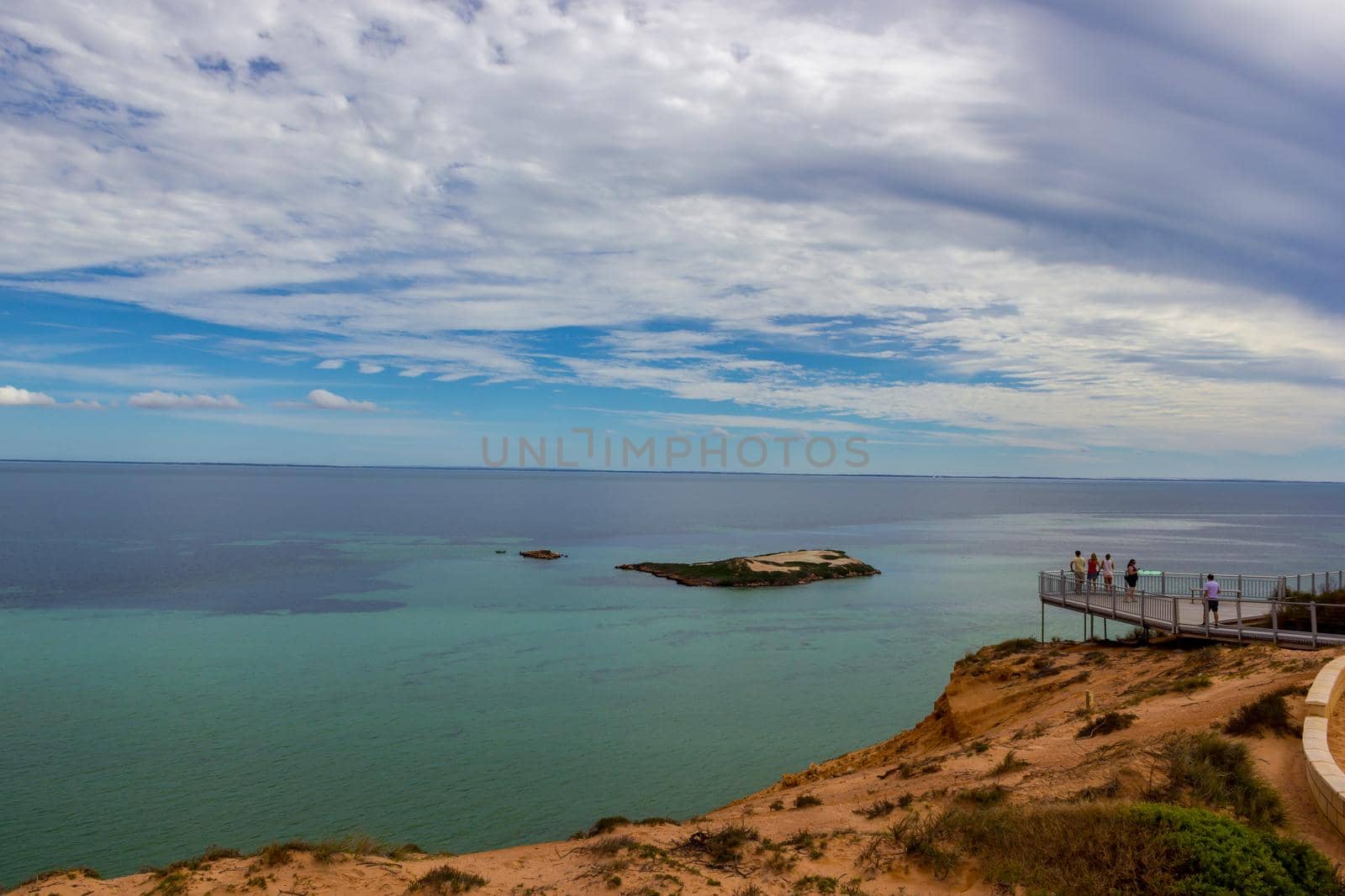 a Group of tourists at a Lookout platform in Monkey Mia, Western Australia. Caucasian girl enjoying cliffs of Indian Ocean coastline. Australian Outback. Blue sky in summer.