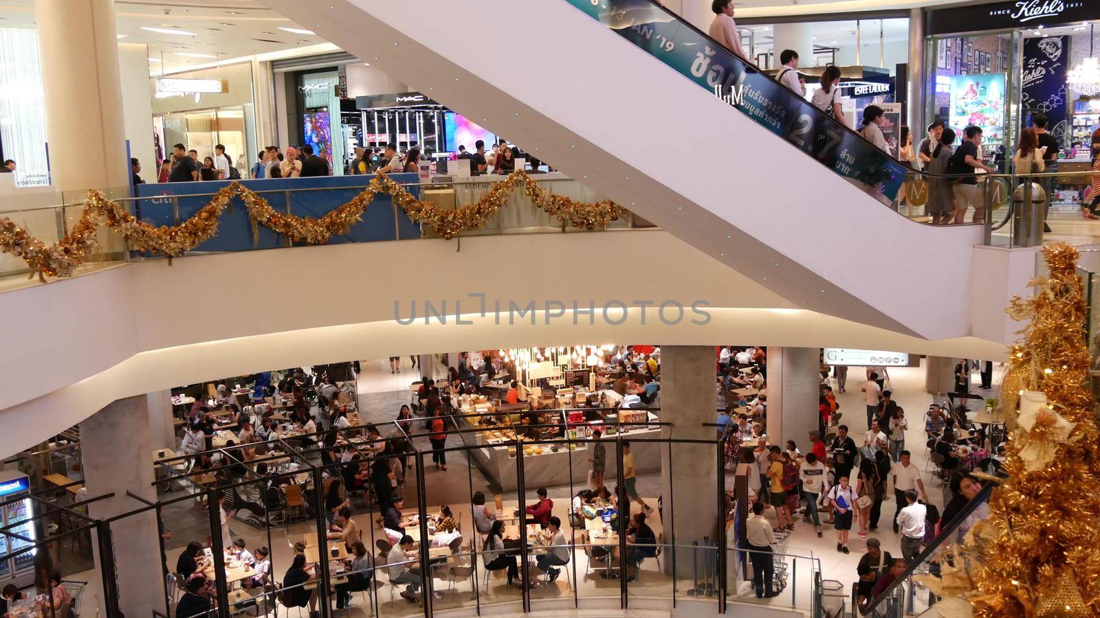 BANGKOK, THAILAND - 18 DECEMBER, 2018: Siam Paragon asian shopping mall interior. Crowds of people on escalators of trade centre. People rush to shopping in modern plaza. Consumption of goods.
