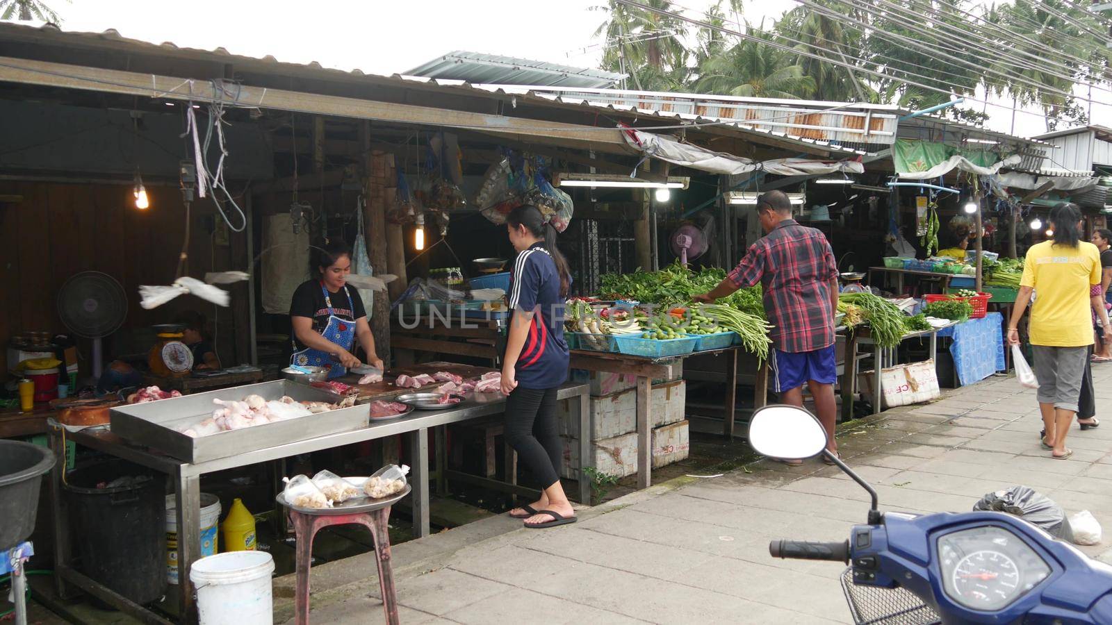 KOH SAMUI ISLAND, THAILAND - 10 JULY 2019: Food market for locals. Lively ranks with groceries. Typical daily life on the street in Asia. People go shopping for fruits vegetables, seafood and meat