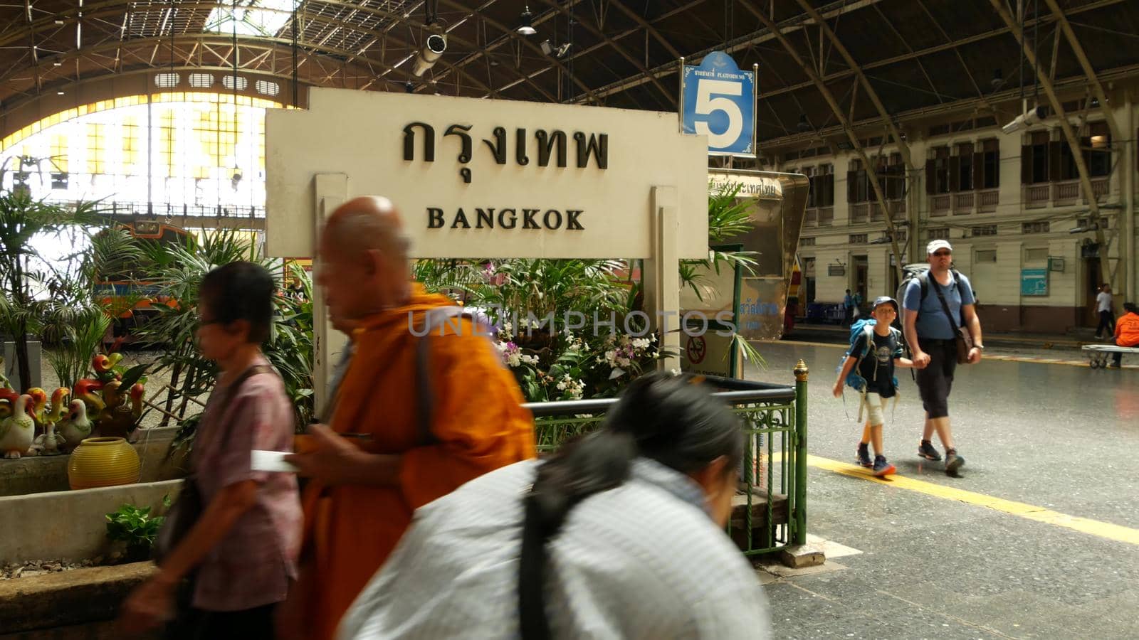 BANGKOK, THAILAND - 11 JULY, 2019: Hua Lamphong railroad station, state railway transport infrastructure SRT. Buddhist holy Monk in traditional orange robe. Monks yellow religious clothes among people by DogoraSun