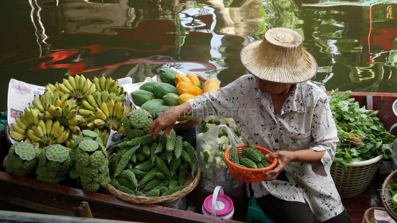 BANGKOK, THAILAND - 13 JULY 2019: Lat Mayom floating market. Traditional classic khlong river canal, local women farmers, long-tail boats with fruits and vegetables. Iconic asian street food selling. by DogoraSun