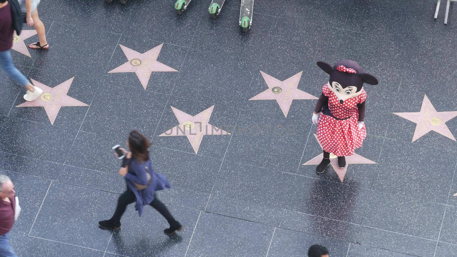 LOS ANGELES, CALIFORNIA, USA - 7 NOV 2019: Walk of fame promenade on Hollywood boulevard in LA. Pedastrians walking near celebrity stars on asphalt. Walkway floor near Dolby and TCL Chinese Theatre.