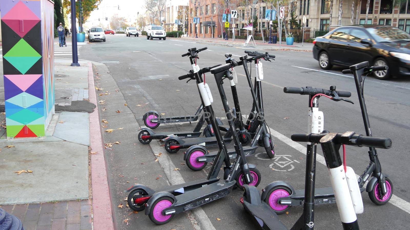 SAN DIEGO, CALIFORNIA USA - 4 JAN 2020: Row of ride sharing electric scooters parked on street in Gaslamp Quarter. Rental dockless public bikes, eco transport in city. Rent kick cycle with mobile app.