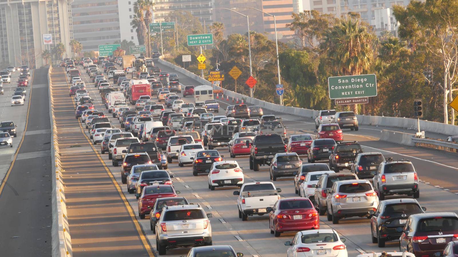 SAN DIEGO, CALIFORNIA USA - 15 JAN 2020: Busy intercity freeway, traffic jam on highway during rush hour. Urban skyline and highrise skyscrapers. Transportation concept and transport in metropolis.