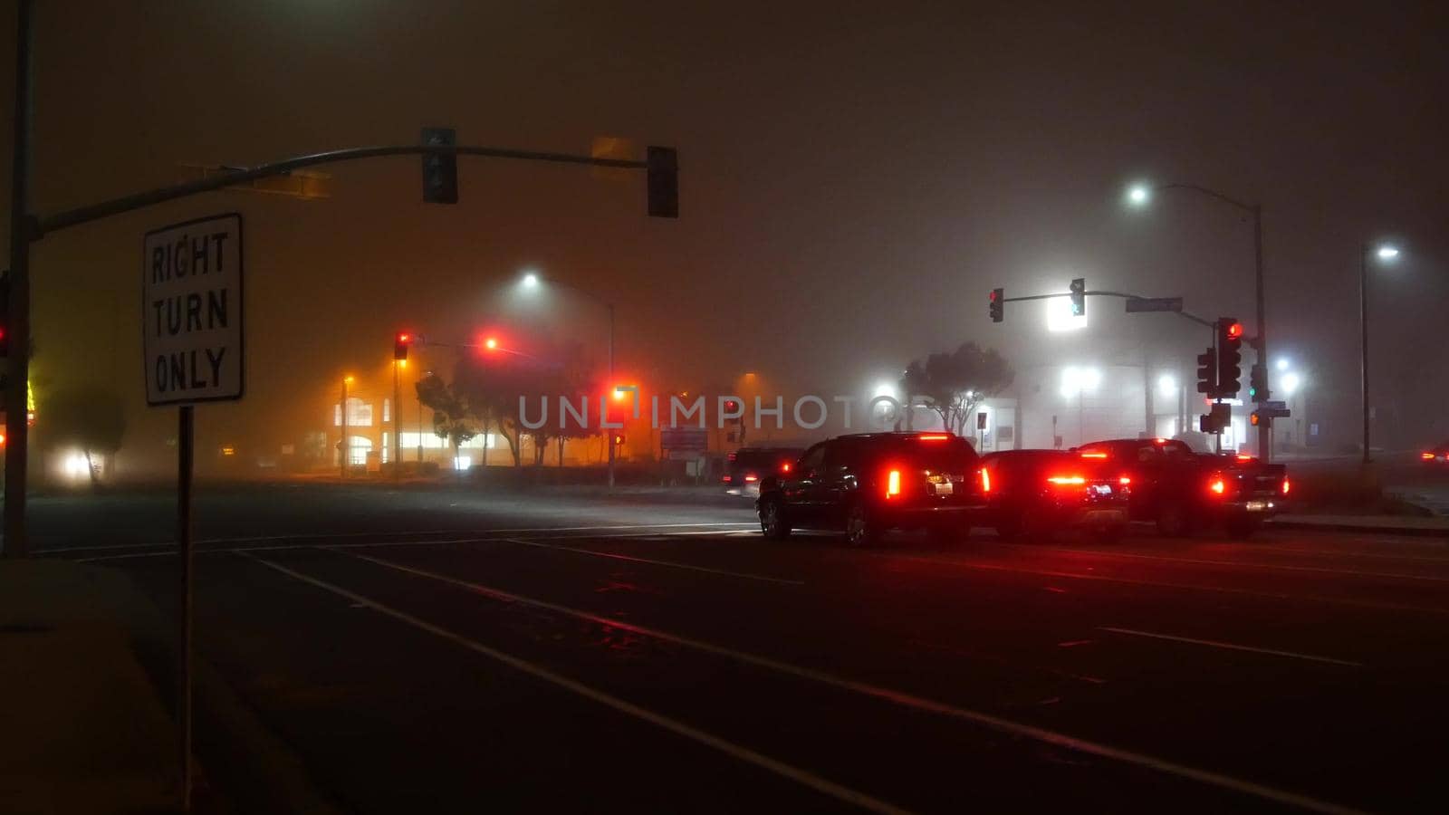 VISTA, CALIFORNIA USA - 24 JAN 2020: Marine layer, dense fog on driveway crossroad at night. June gloom, misty nebulous bad weather. Dangerous low visibility on road intersection. Car traffic safety by DogoraSun