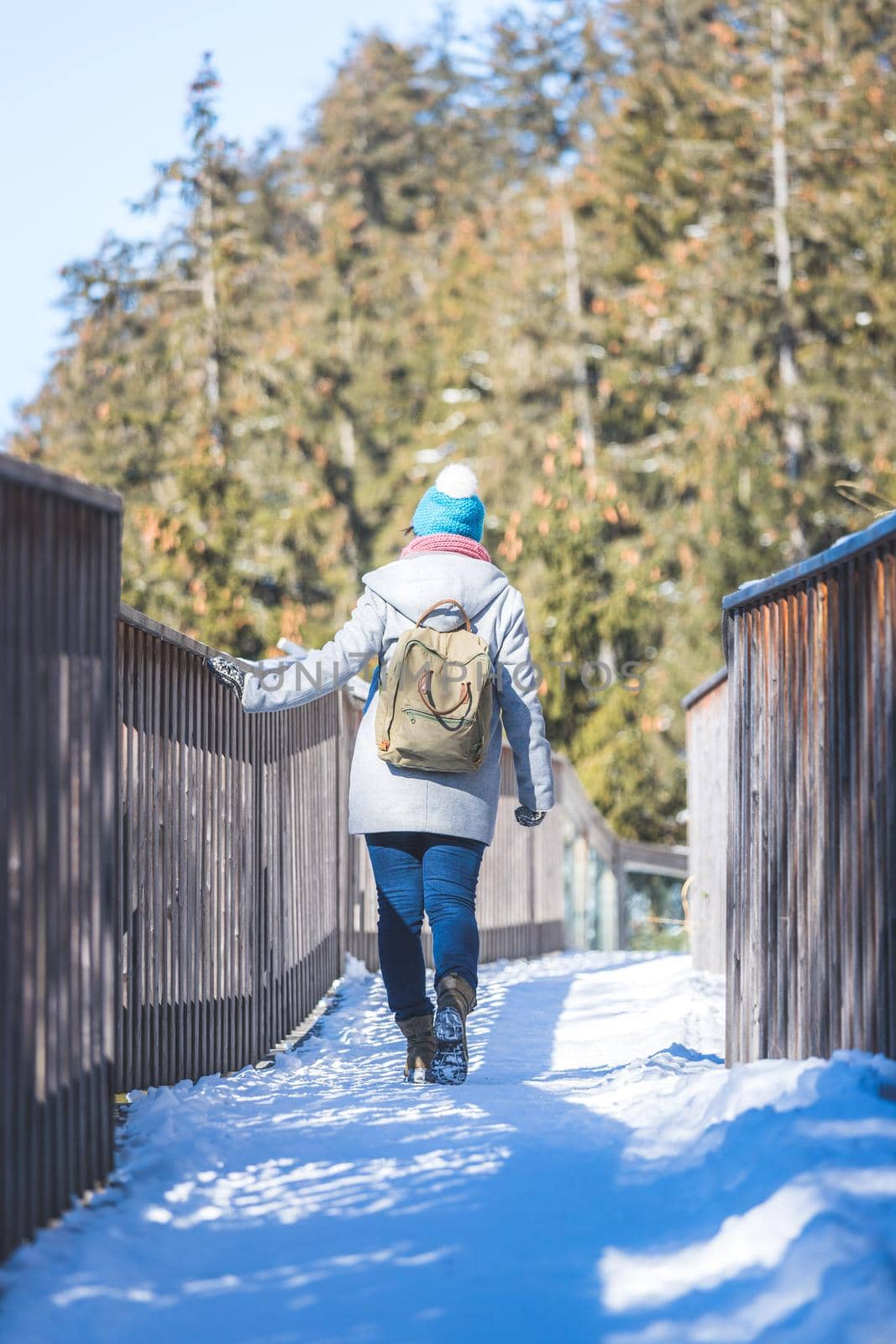 Young woman is walking on snowy wooden bridge