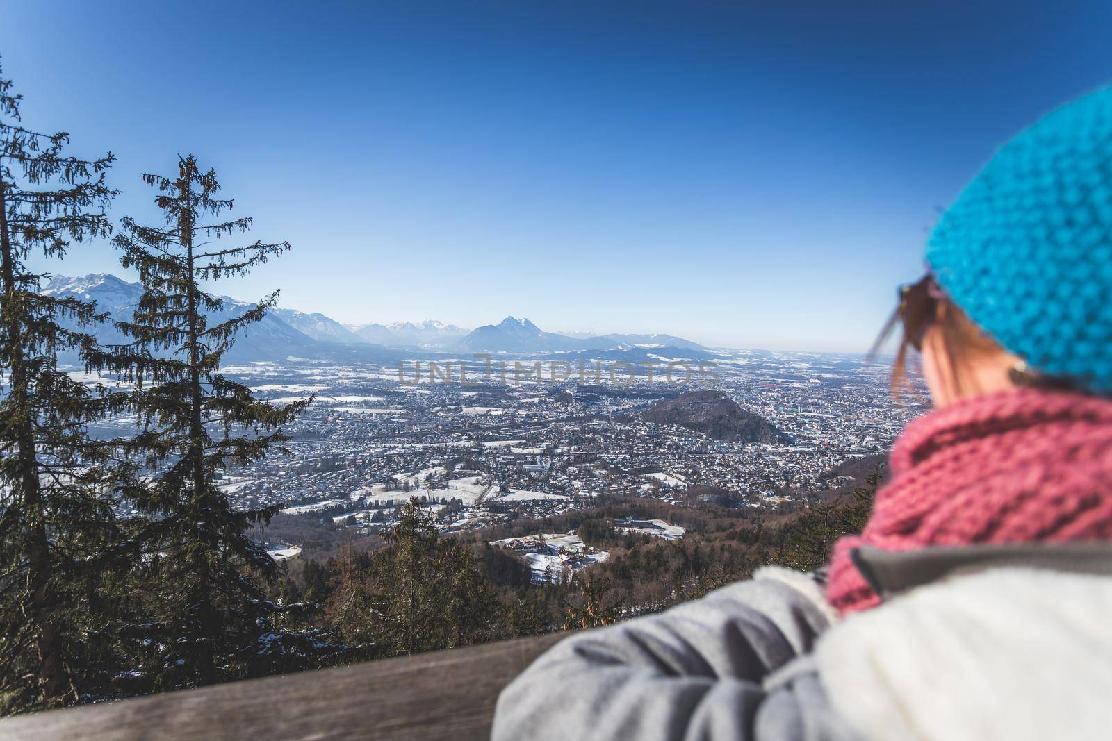 Happy young woman is enjoying the view over the mountains and Salzburg. Winter time on Gaisberg, Salzburg, Austria by Daxenbichler