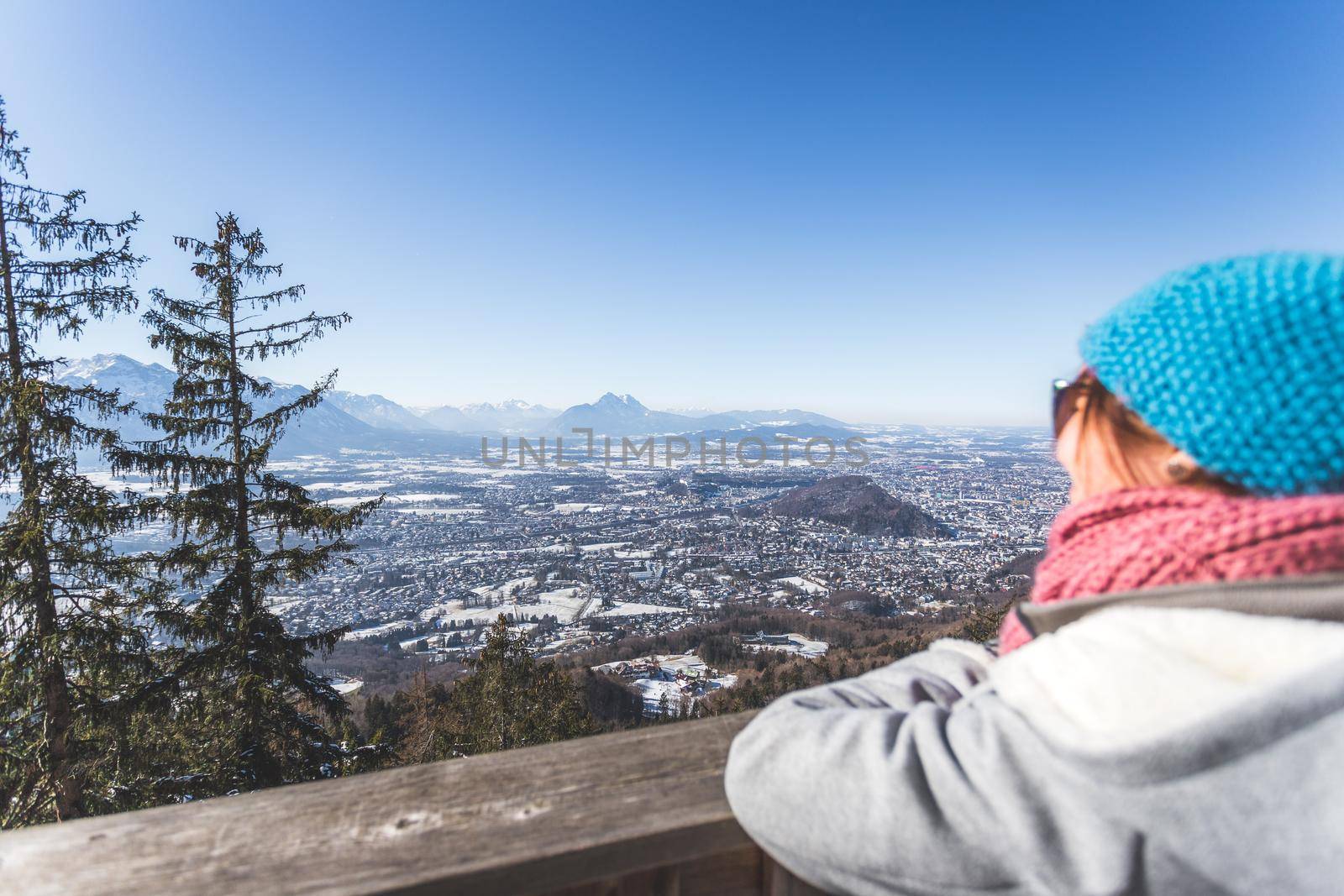 Happy young woman is enjoying the view over the mountains and Salzburg. Winter time on Gaisberg, Salzburg, Austria by Daxenbichler