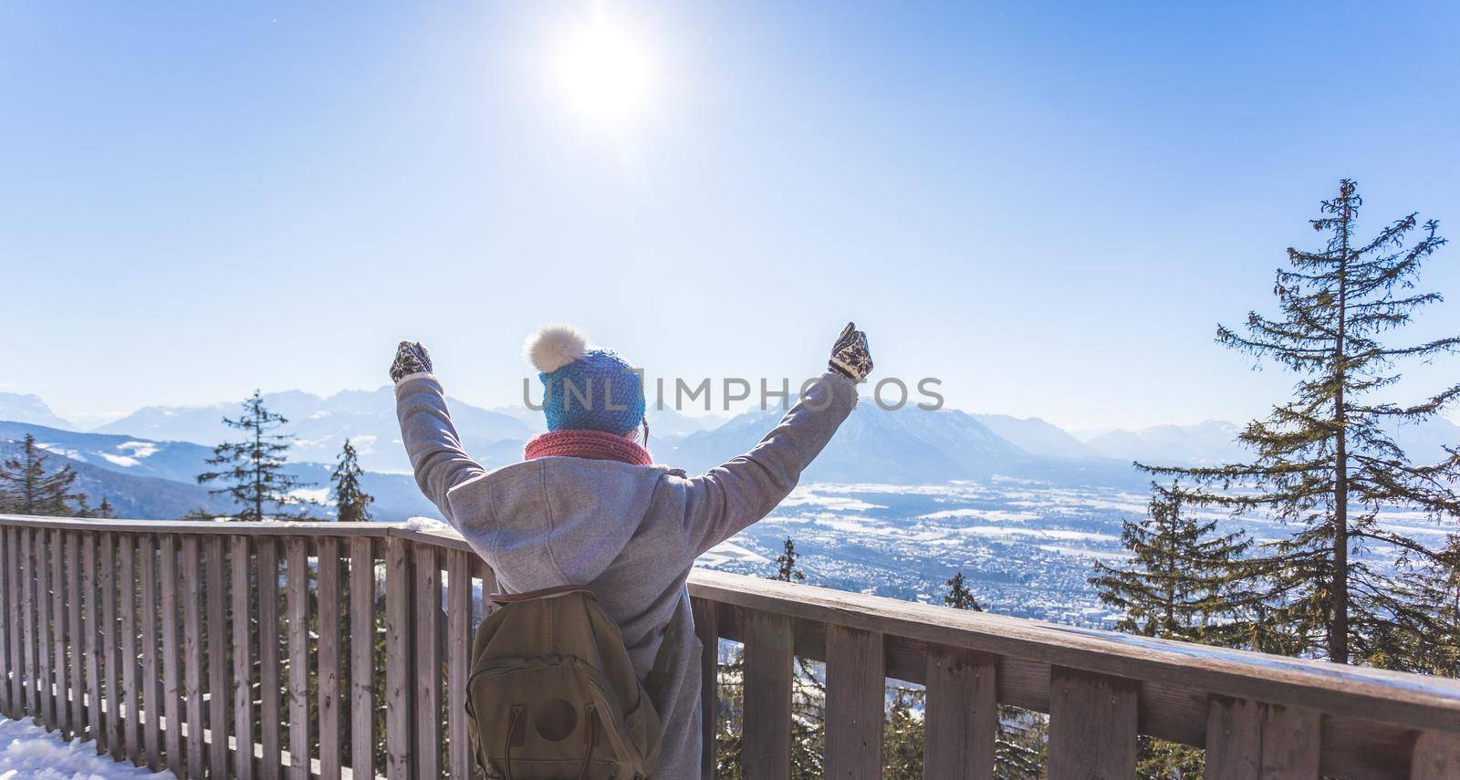 Back of young woman who is raising her hands on the mountain, outlook. Gaisberg, Austria