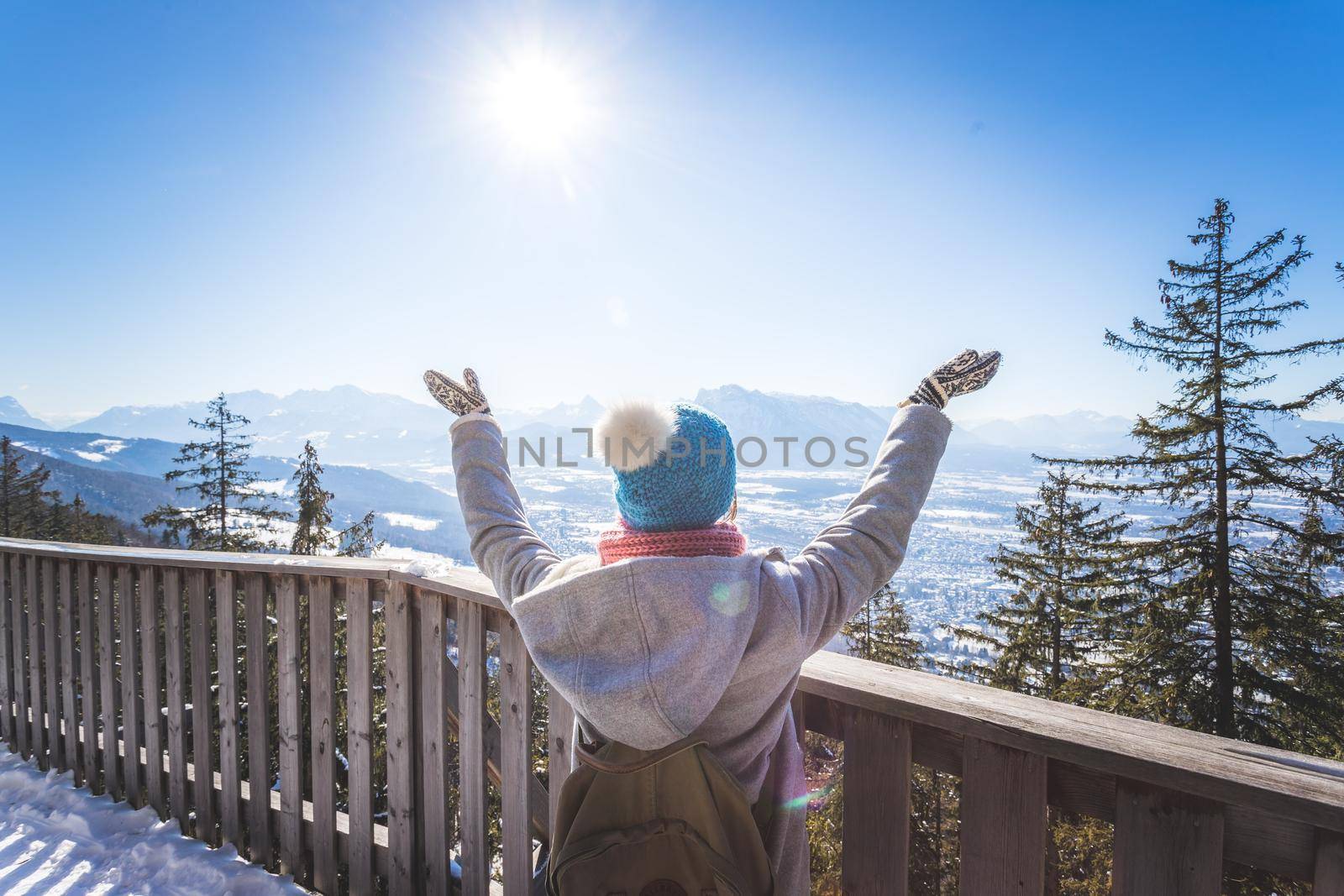 Happy young woman is raising her hands on the mountain, enjoying the view over Salzburg. Winter time on Gaisberg, Salzburg, Austria by Daxenbichler