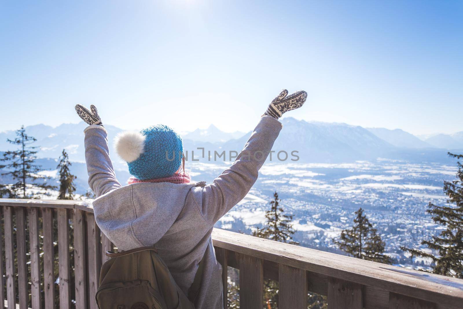 Back of young woman who is raising her hands on the mountain, outlook. Gaisberg, Austria