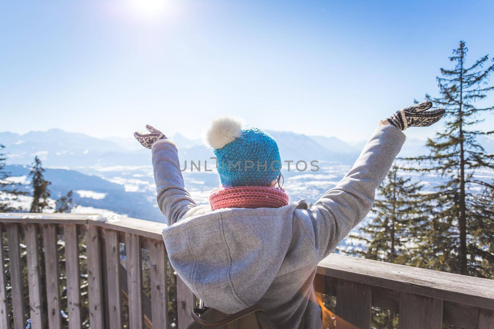 Happy young woman is raising her hands on the mountain, enjoying the view over Salzburg. Winter time on Gaisberg, Salzburg, Austria by Daxenbichler