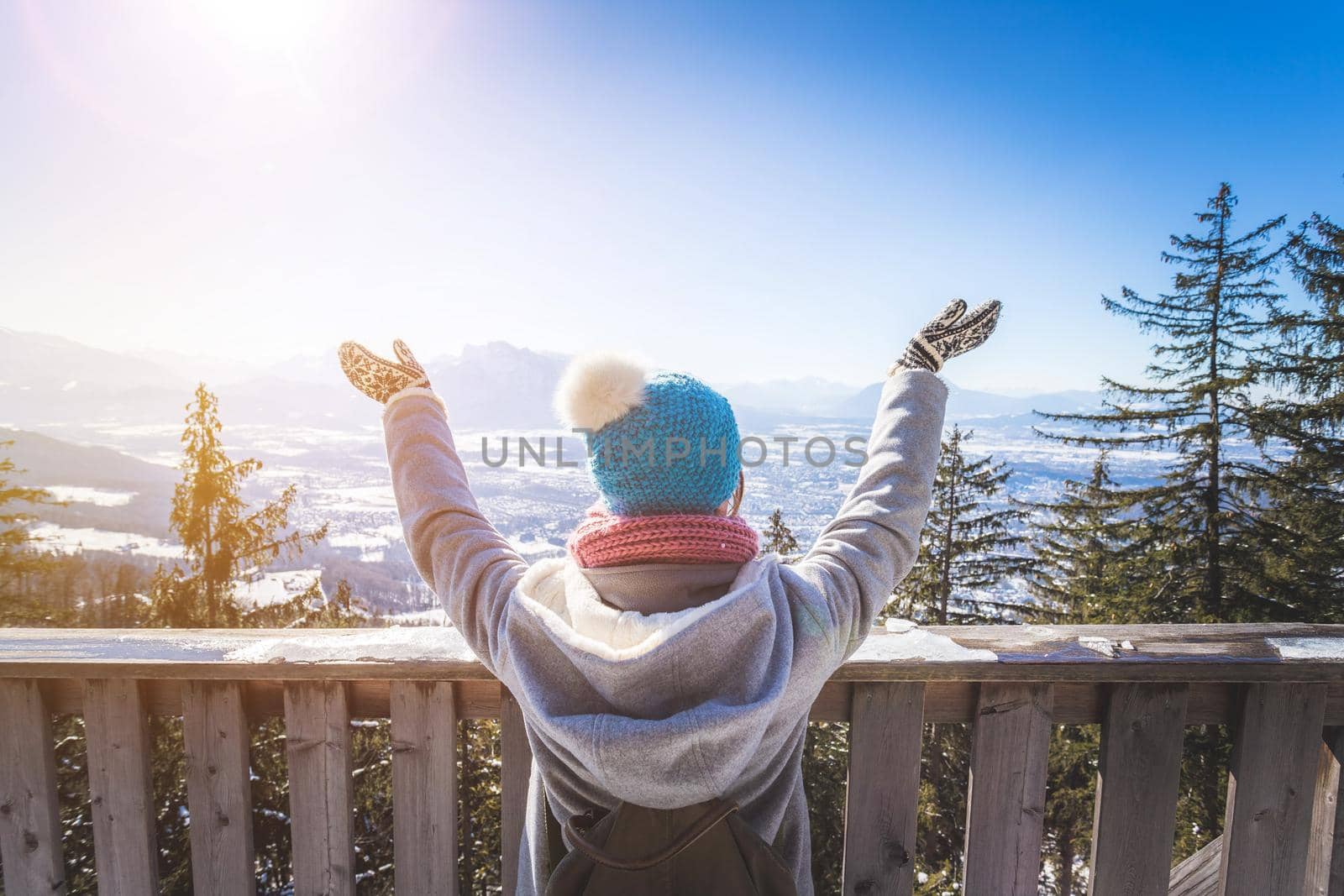 Happy young woman is raising her hands on the mountain, enjoying the view over Salzburg. Winter time on Gaisberg, Salzburg, Austria by Daxenbichler