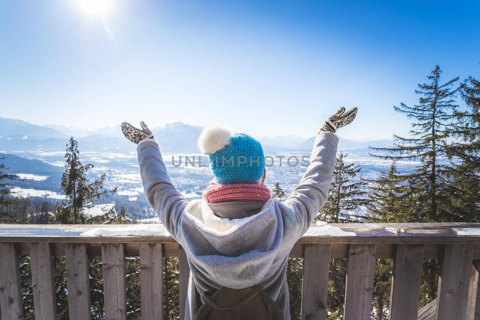 Back of young woman who is raising her hands on the mountain, outlook. Gaisberg, Austria