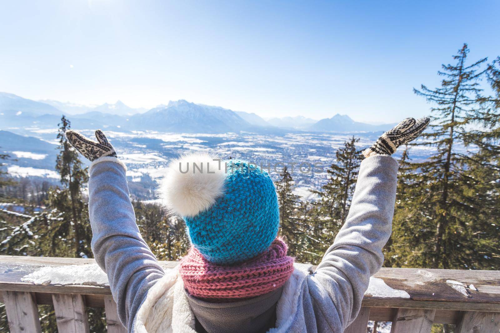 Back of young woman who is raising her hands on the mountain, outlook. Gaisberg, Austria