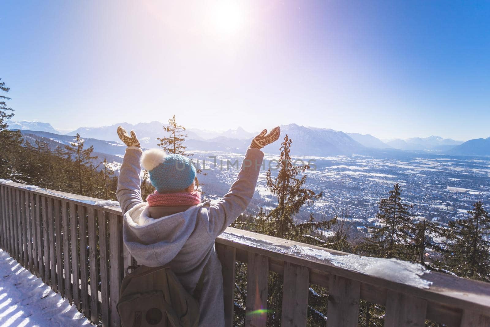 Back of young woman who is raising her hands on the mountain, outlook. Gaisberg, Austria