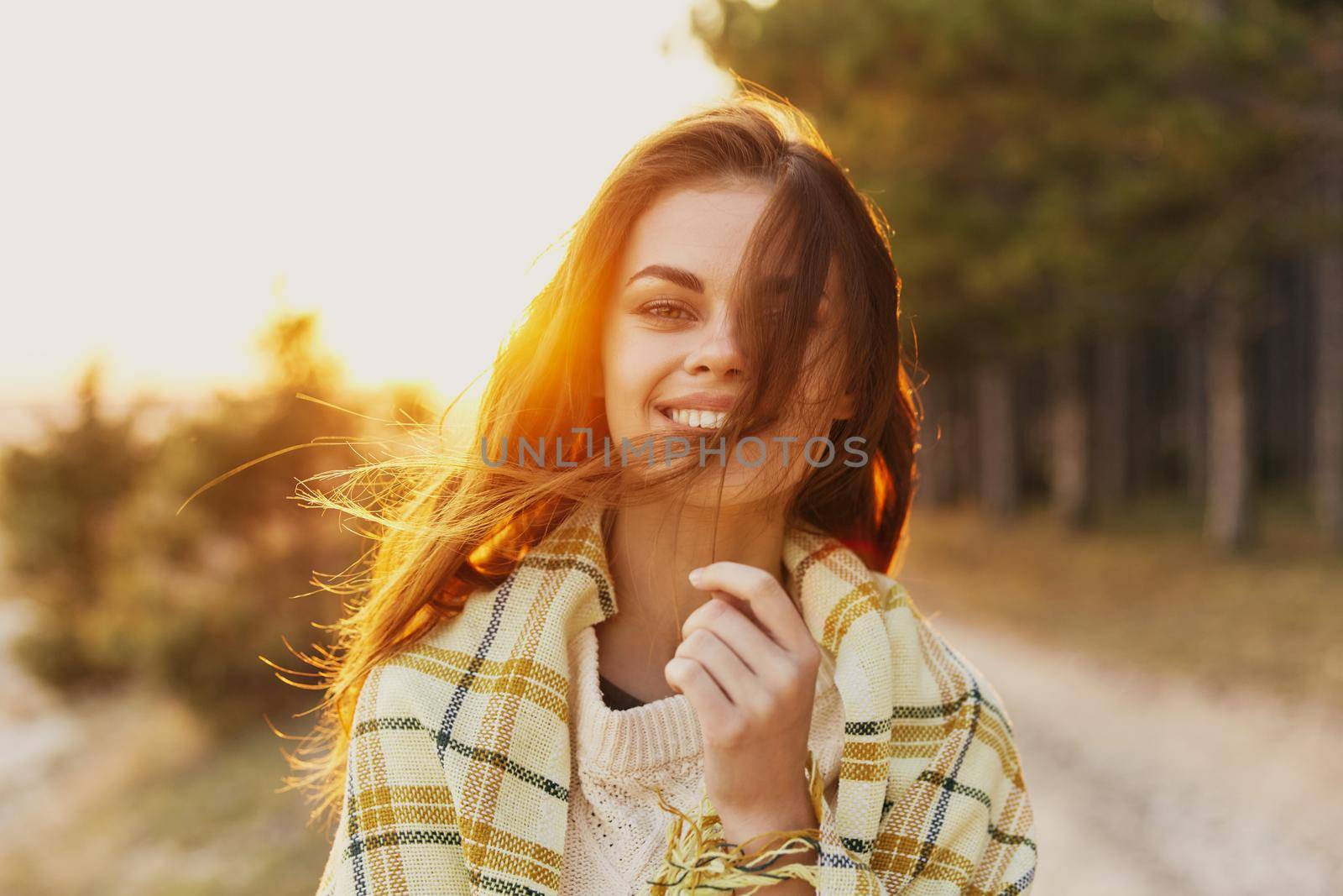 Happy woman in nature near coniferous trees and bright sunlight in the background by SHOTPRIME