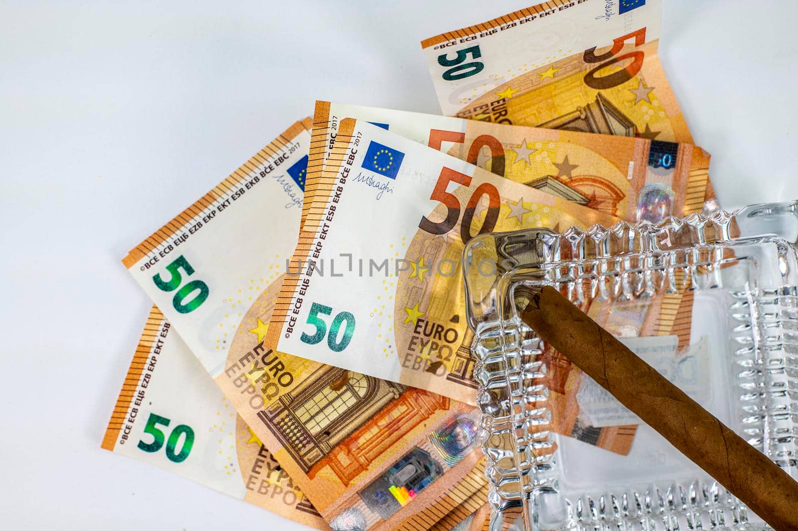 50 euro bills with cigar and ash holder on white background