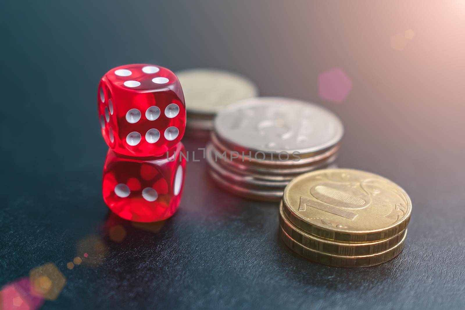 Dice, coins and chips of different denominations in a casino in light reflections